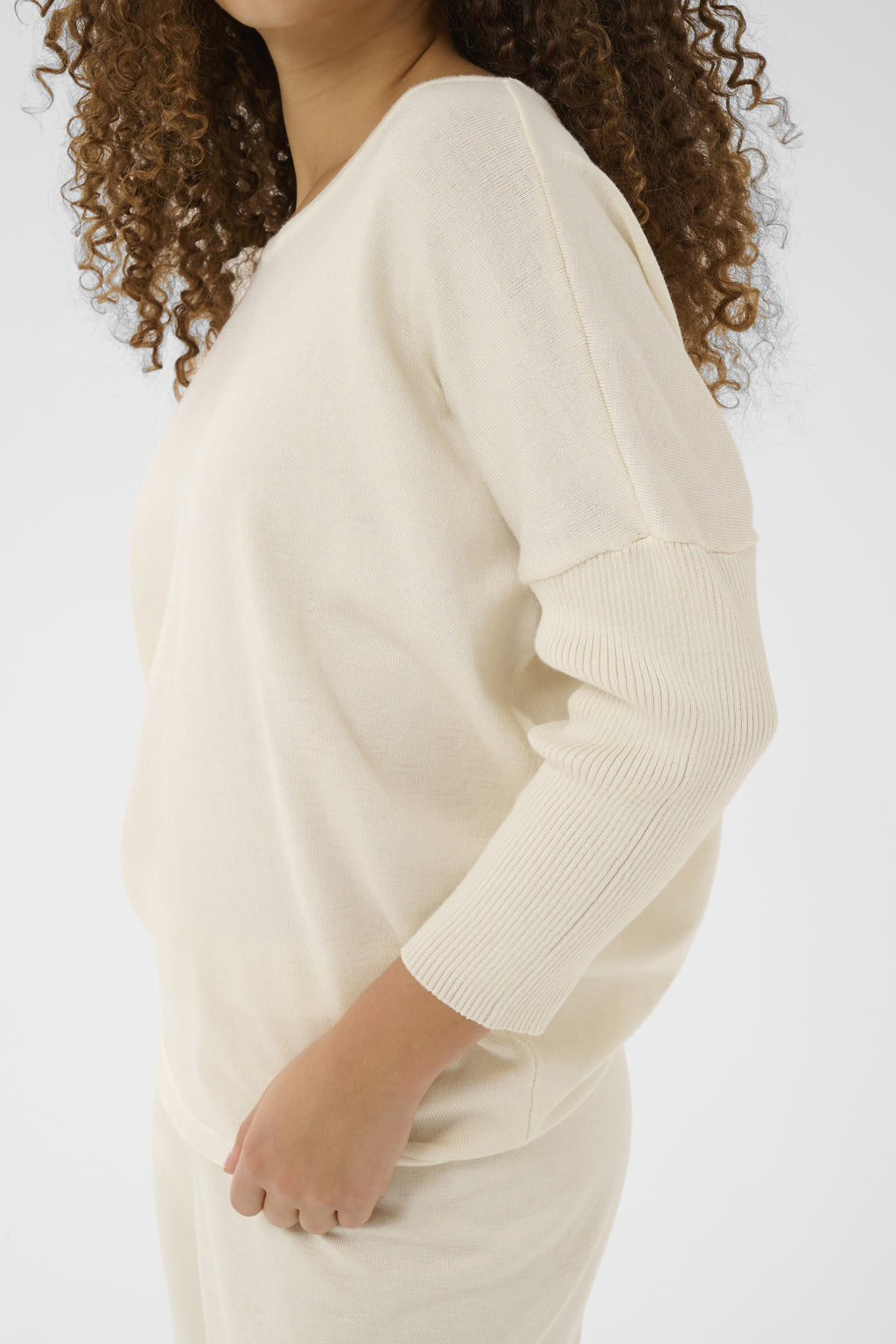 Person wearing a cream sweater against a white background