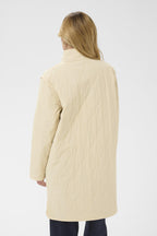 Woman wearing a beige quilted coat on a white background