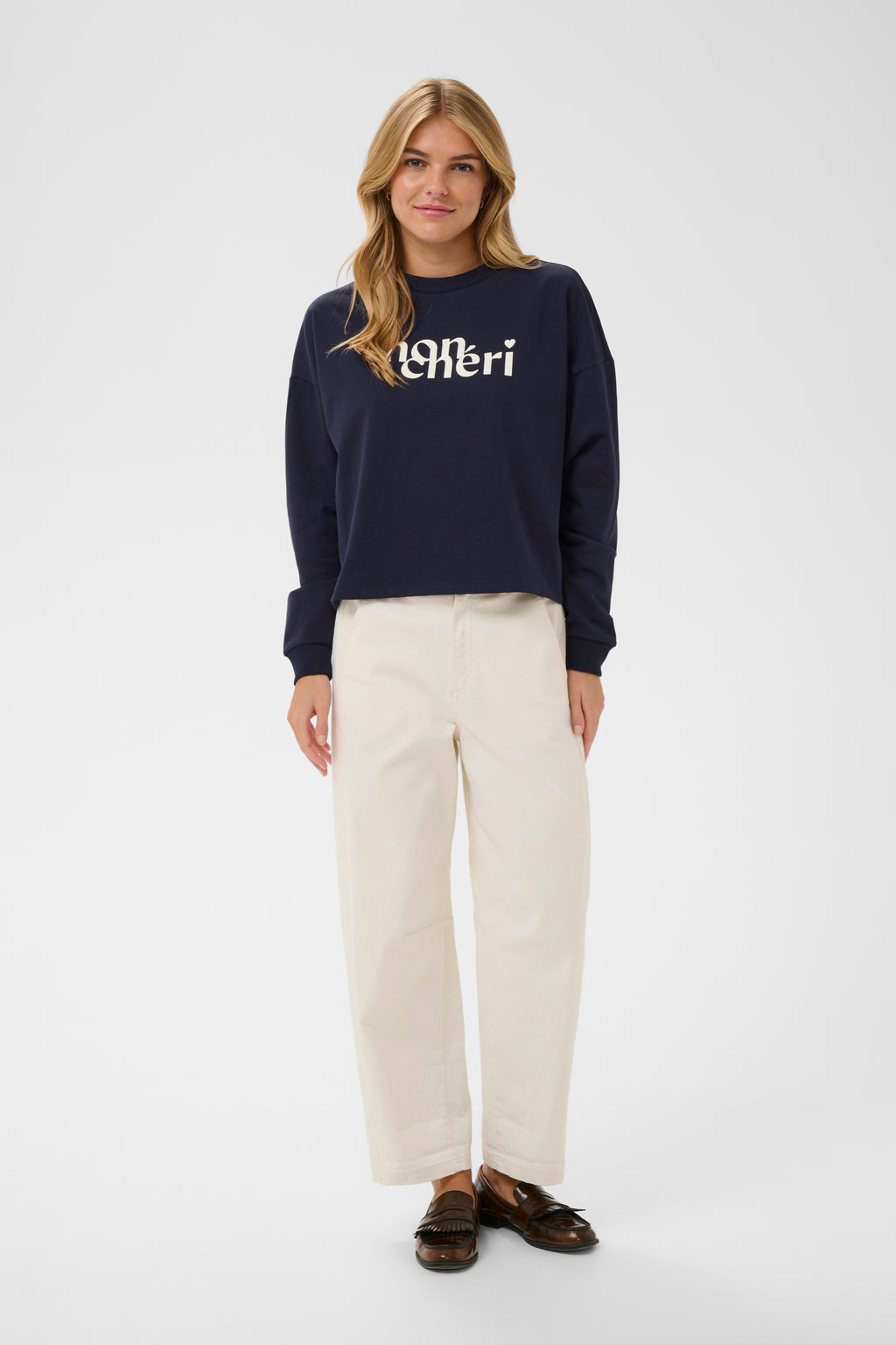 Woman wearing a navy sweater with a brand logo on a white background