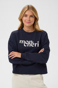 Woman wearing a navy blue sweatshirt with 'mon cheri' text on a white background