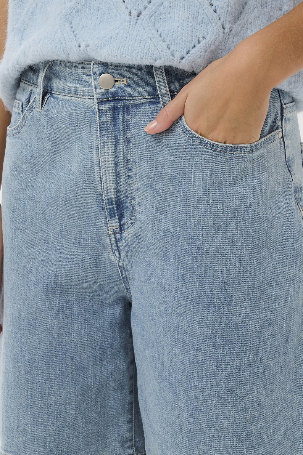 Light blue jeans worn by a person with a light blue textured top.