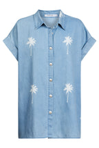 Blue denim shirt with white palm tree designs on a white background
