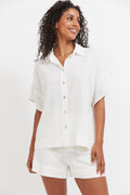 Woman wearing a white shirt and shorts on a plain background