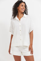 Woman wearing a white shirt and shorts on a plain background