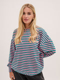 Woman wearing a striped shirt with pink and green horizontal stripes on a plain background