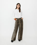 Woman wearing leopard print pants and a white top on a white background