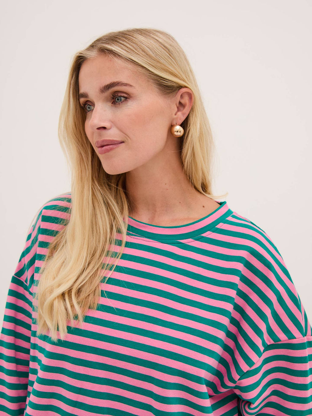 Woman wearing a pink and green striped shirt against a light background