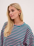 Woman wearing a pink and green striped shirt against a light background