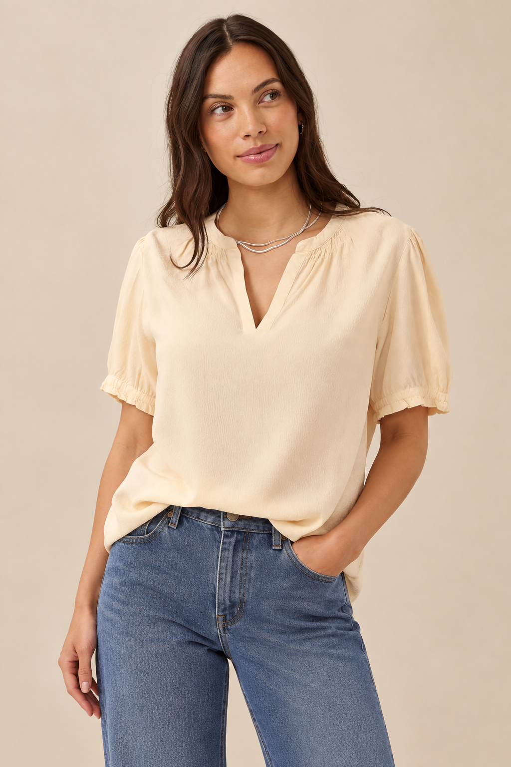 Cream blouse styled with jeans against a neutral background