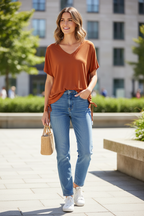 Rust orange top untucked with jeans and trainers