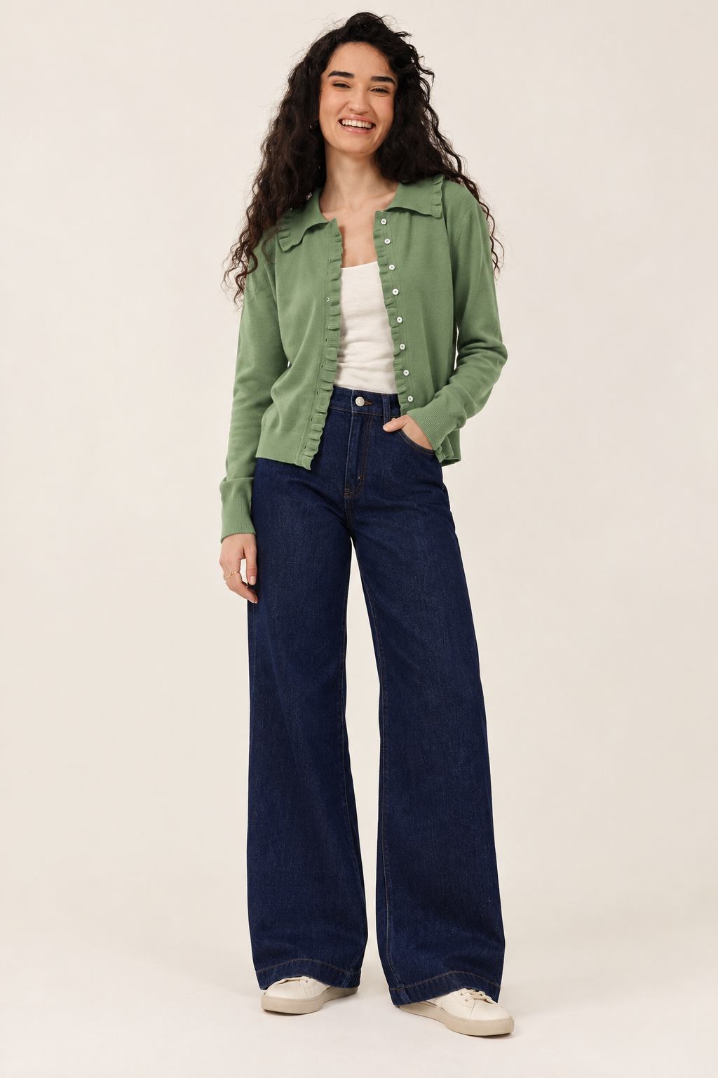 Sage-green top and dark denim jeans styled with cream trainers