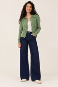 Sage-green top and dark denim jeans styled with cream trainers