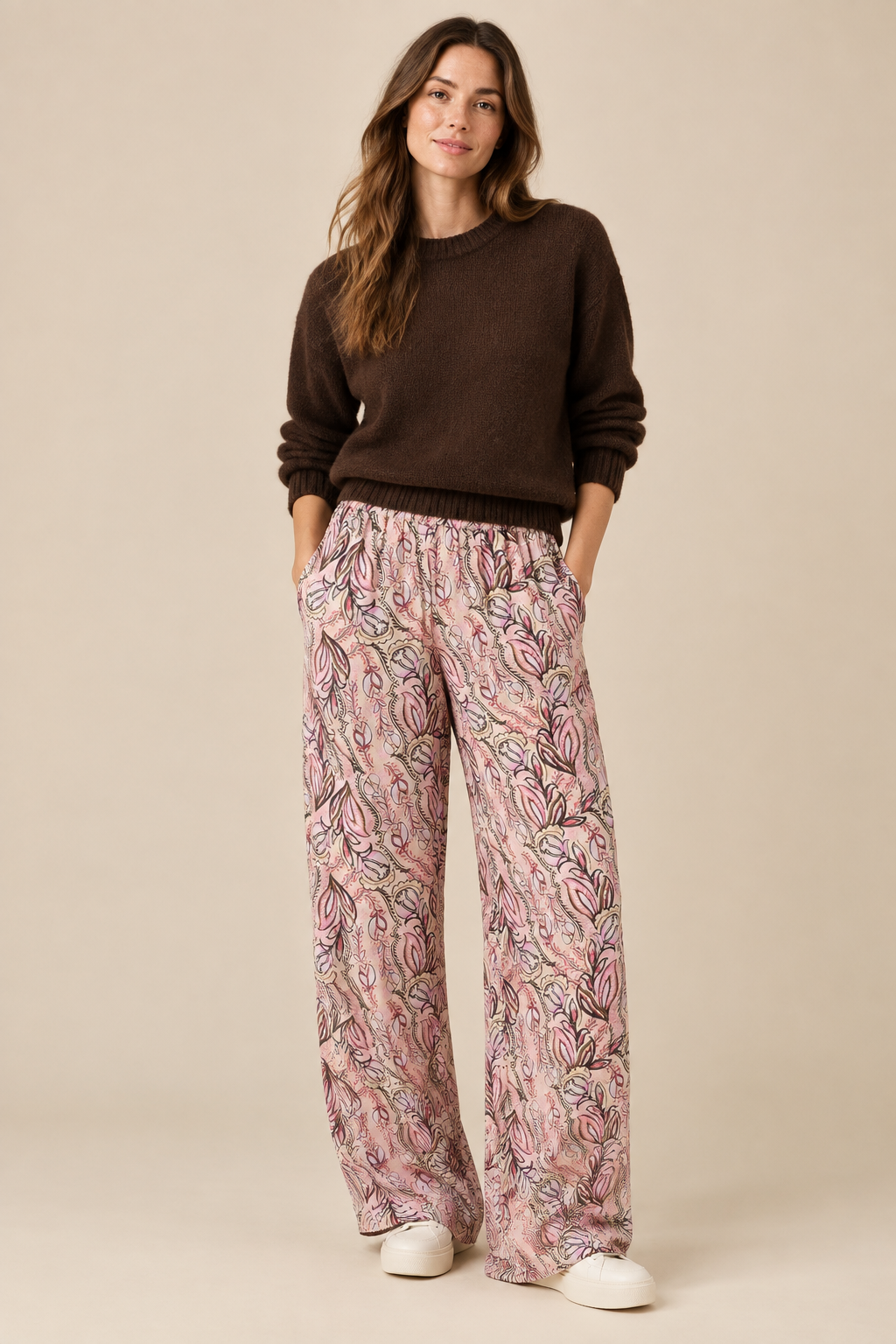 Styled pink printed trousers with a brown jumper and trainers